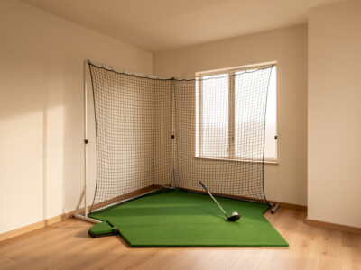Apartment corner converted into a compact golf net practice station under a low ceiling