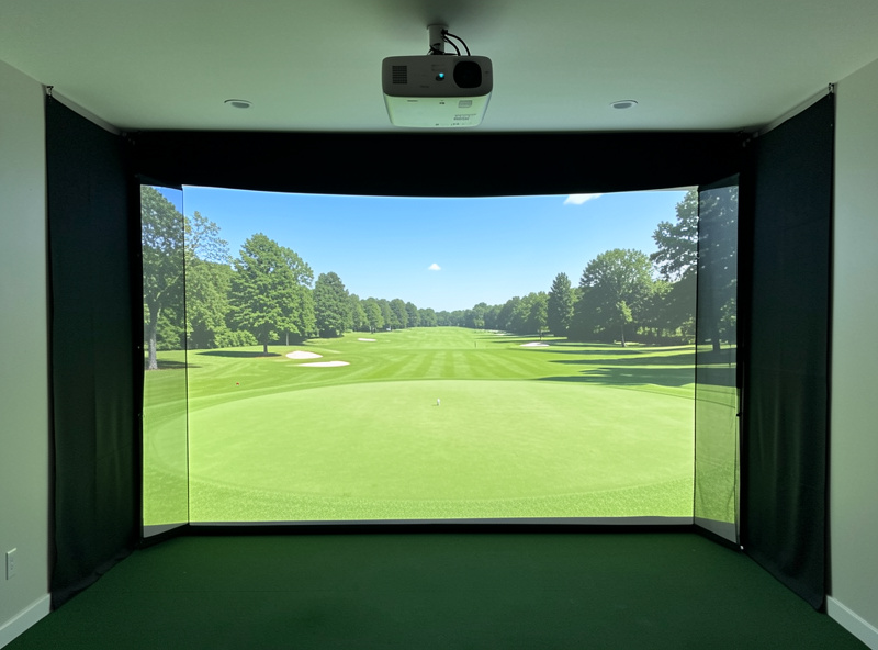 Home golf simulator with a bright evenly lit course image filling the impact screen from a ceiling short-throw projector