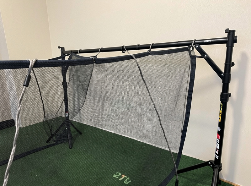 Impact screen hung with deliberate slack and an air gap behind it for safe bounce-back in a golf simulator