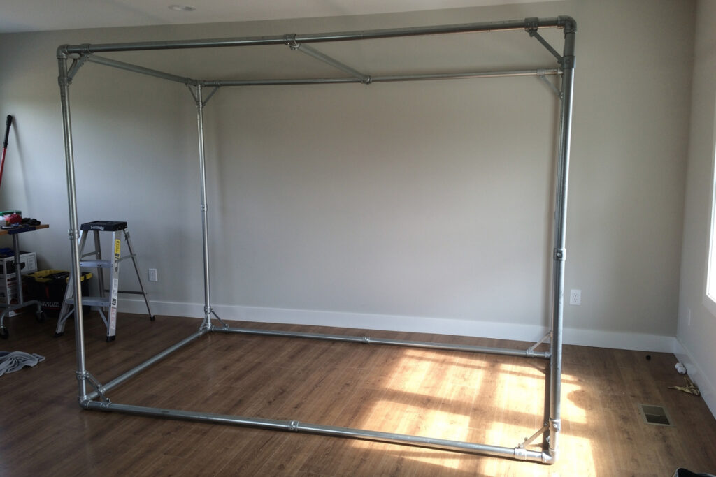 Completed EMT conduit golf simulator enclosure frame in a home room