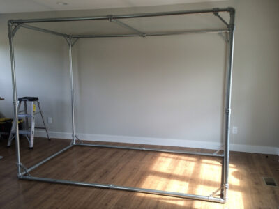 Completed EMT conduit golf simulator enclosure frame in a home room
