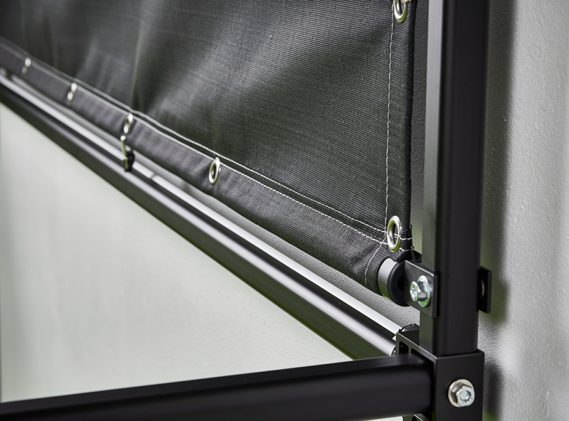 Tensioned multi-layer golf impact screen hung with standoff from the wall inside an enclosure frame